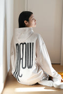 Back view of model wearing Toby Black cream hoodie with large black MEOW graphic and small cat icon