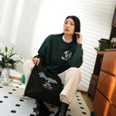 Model sitting with black "Live Like A Cat" tote bag.
