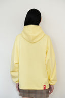Back view of yellow oversized hoodie with red cat logo tag