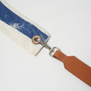 Leather strap attachment with silver clasp and eyelet on blue striped bag