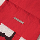 "Interior detail of WHY NOT? Toby Bag showing Toby Black engraved metal logo plate on red nylon"