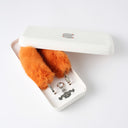 Orange fluffy keychain with metal clips in a white box on a light gray background
