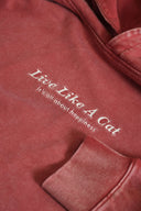 Close-up of red Vintage hoodie showing "Live Like A Cat - it's all about happiness" embroidered text detail