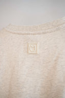 Cream rubber cat logo patch on back neckline of gray sweatshirt.