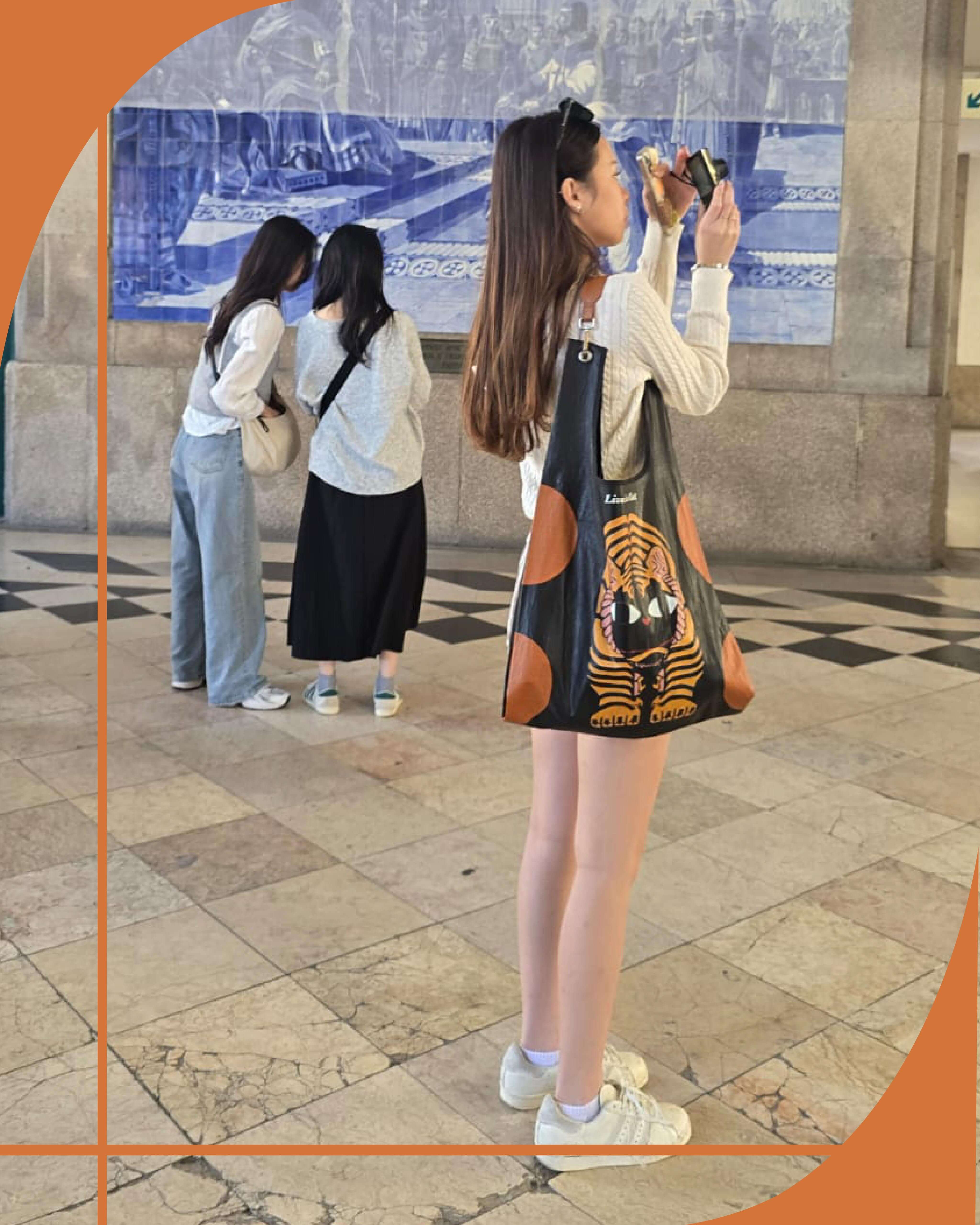 Woman taking a photo with a tiger-patterned bag in an urban setting