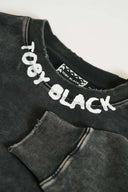 Detailed view of hand-painted white Toby Black logo on charcoal ribbed neckline with brand label