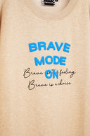 Beige sweatshirt with blue and black text 'Brave Mode ON' on a beige background