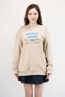 Model wearing beige Brave Mode sweatshirt with denim skirt
