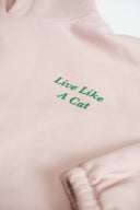Close-up of green "Live Like A Cat" embroidery text