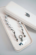 Silver key-shaped charms on a Wrist Strap in a white jewelry box with a small elephant design.