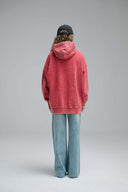 Back view of model wearing red Live Like A Cat hoodie with wide-leg jeans and black cap