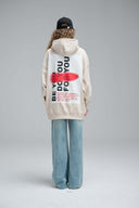 Back view of model wearing Toby Black cream hoodie with "BE YOU DO YOU FOR YOU" graphic and black cap