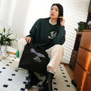 Woman sitting with black Toby Bag, bright room with furniture